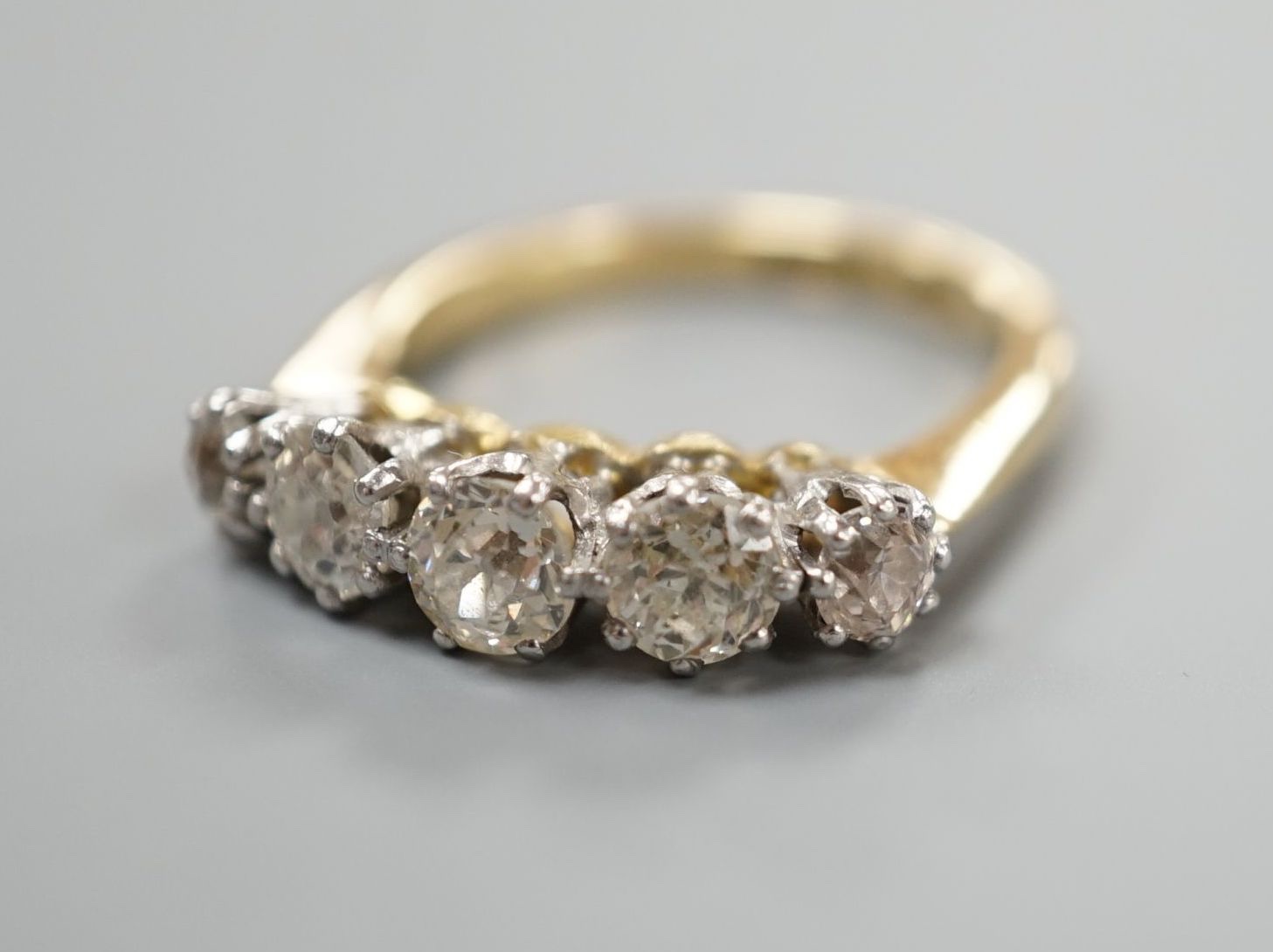 An 18ct and graduated five stone diamond set half hoop ring, size K, gross weight 4 grams.